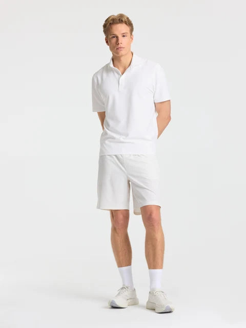 Full-body view of a man wearing white CASPARA Prime Core shorts and a white polo shirt.